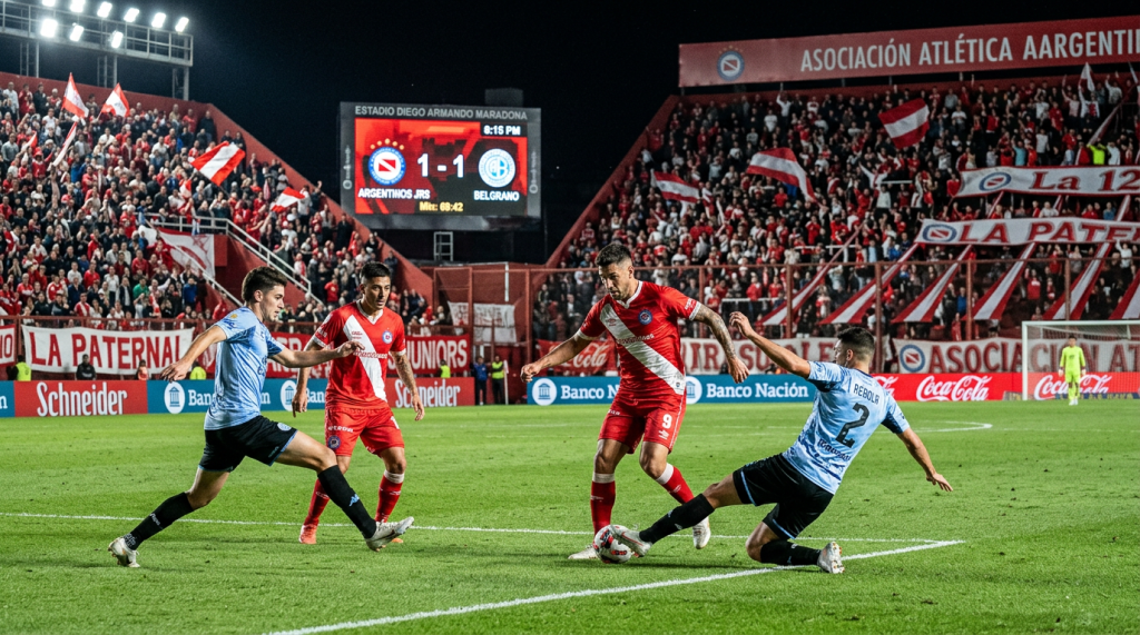 Soccer players from Argentinos Juniors and Belgrano contesting for the ball near the goal